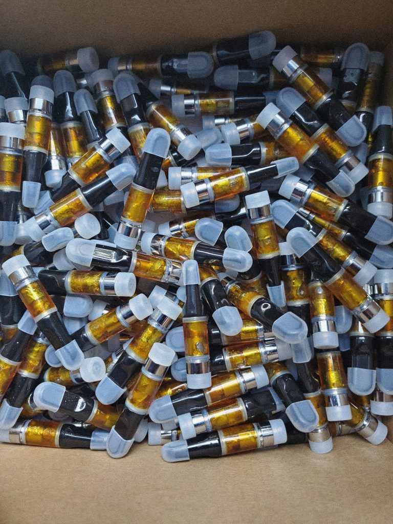 DMT vape cartridge ultimate guide: bulk pile of yellow-amber oil carts in box – visual reference for effects, dosage, purity assessment, testing and harm reduction