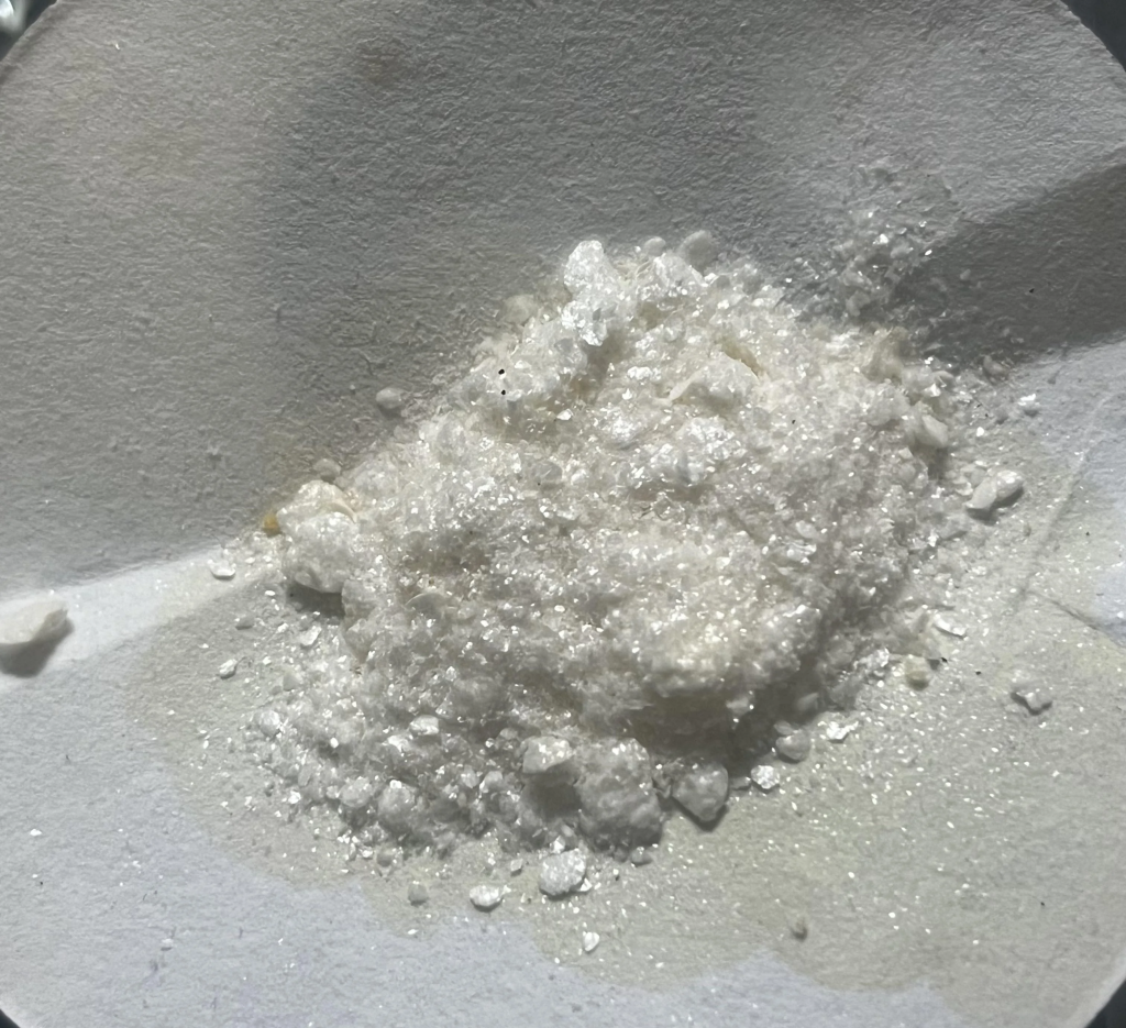 Mescaline HCl powder ultimate guide: close-up of white crystalline chunks and fine shards on paper surface – visual reference for effects, dosage, purity assessment, testing and harm reduction