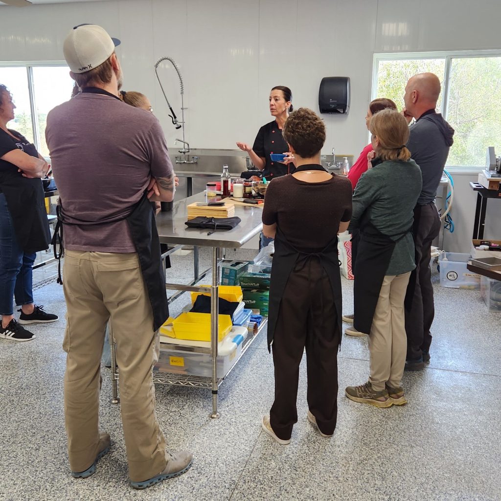 A diverse group of people sitting together in a professional, brightly lit workshop setting for a psychedelic harm reduction and education session.