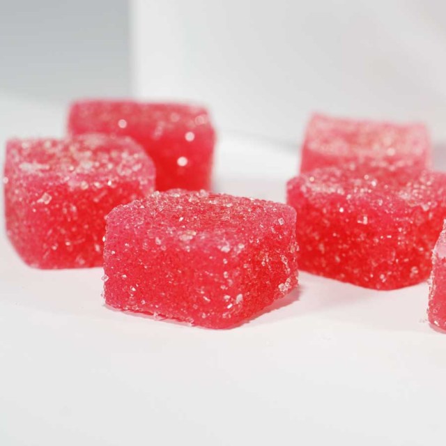 Macro photograph of red, sugar-coated MDMA Gummies designed for the 2026 Gummy Protocol. The image highlights the uniform, micro-calibrated square shape used for precision splitting and titration in PTSD therapeutic settings, ensuring metabolic smoothing and consistent dosing.