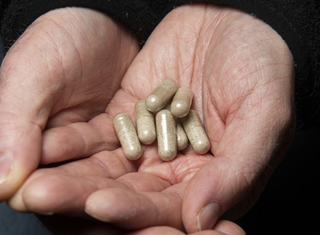 Standardized microdose magic mushroom capsules held in two hands to demonstrate the precision purity calibration.