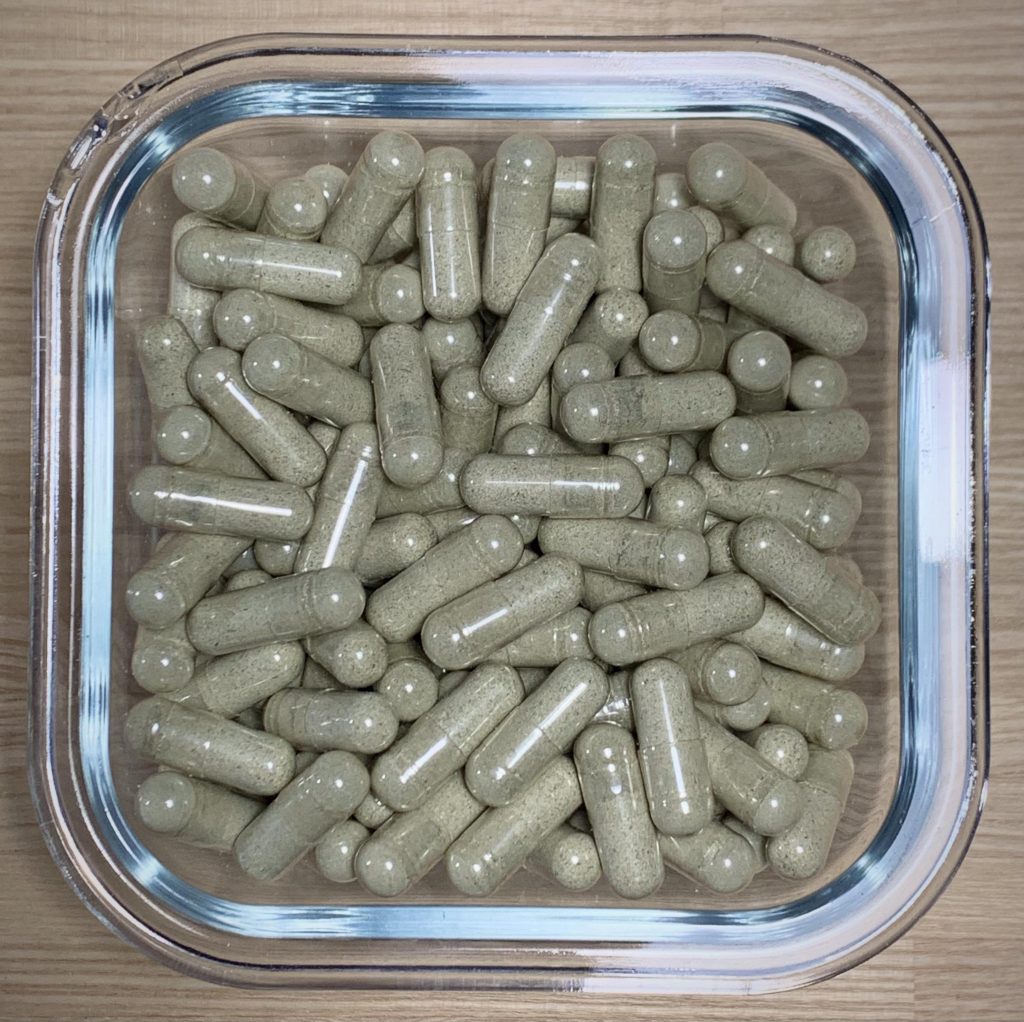 Batch of lab-verified magic mushroom capsules filled with micro-pulverized psilocybin powder.