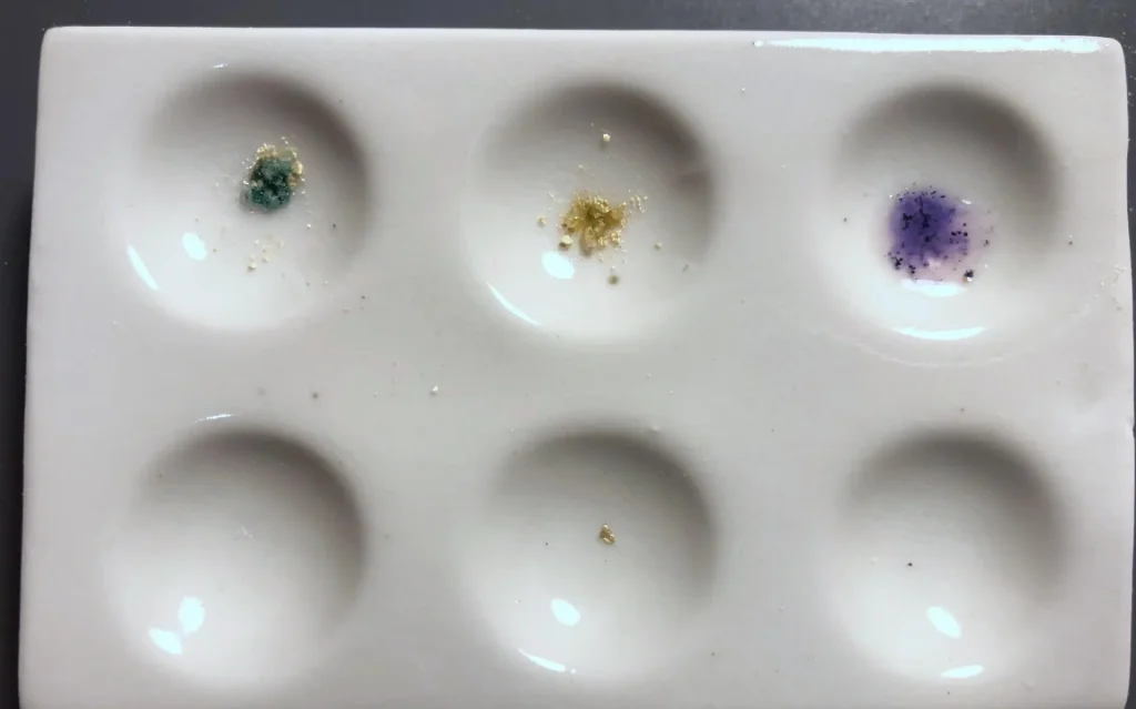 Multi-reagent drug testing kit color reactions on a white ceramic spot plate during 2C-B purity verification.